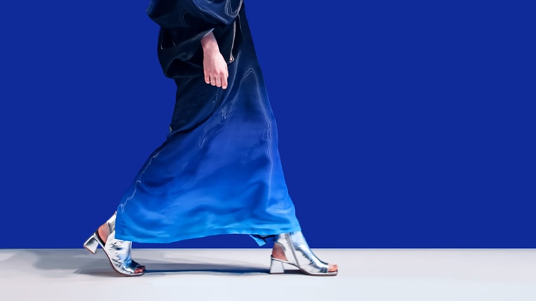 A woman struts down the runway in a creative blue designer satin dress