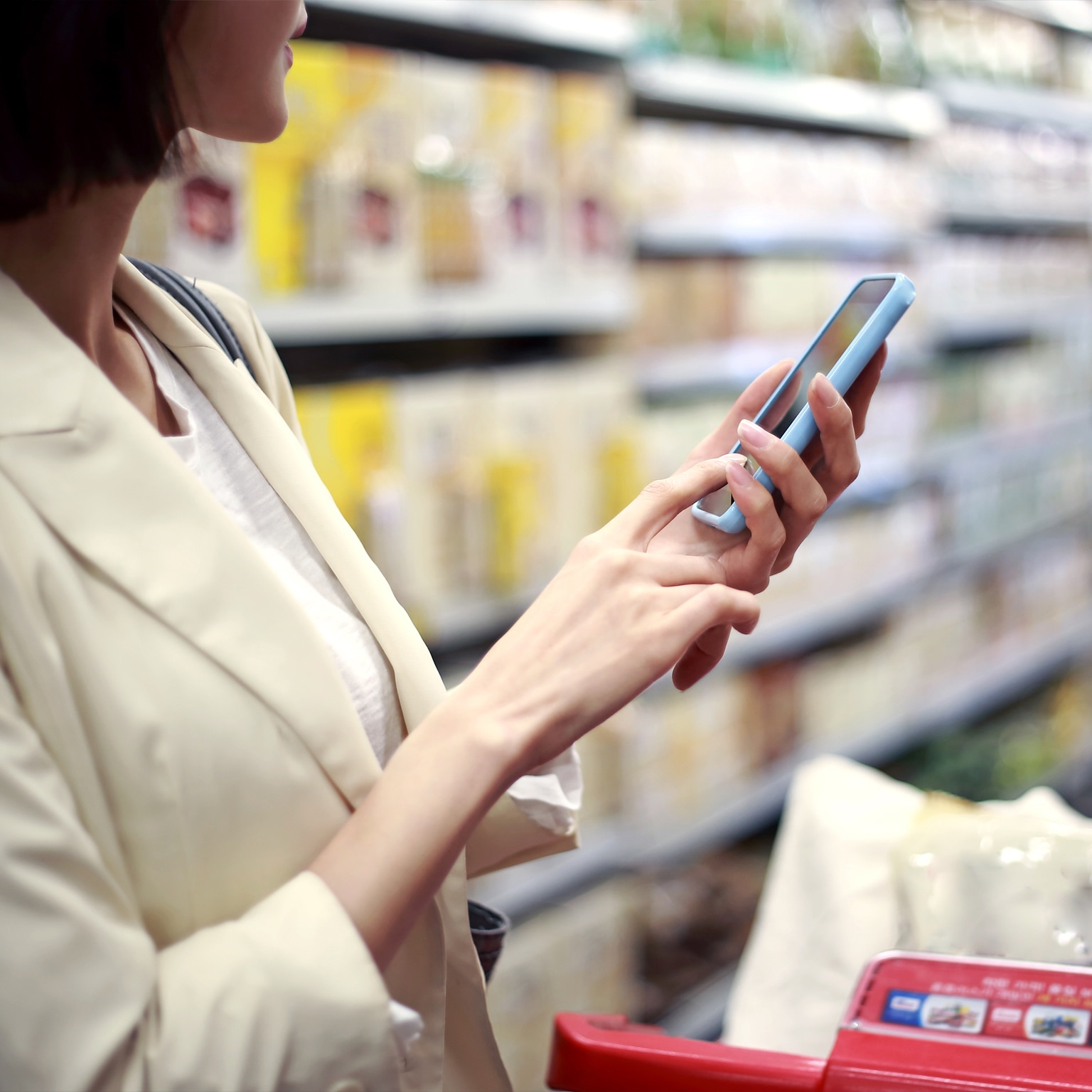 Woman using cell phone, grocery shopping in market - stock photo