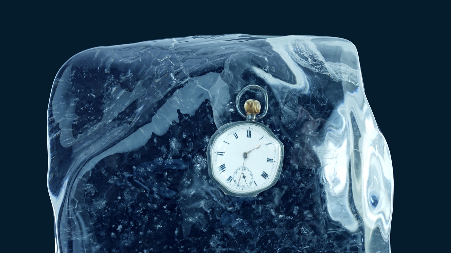 A pocket watch encased in a block of ice and set against a deep blue backdrop.