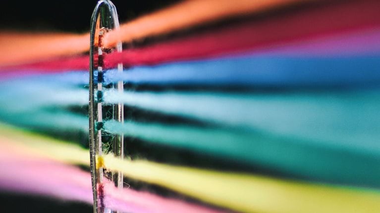 Needle of sewing and its colored threads - stock photo