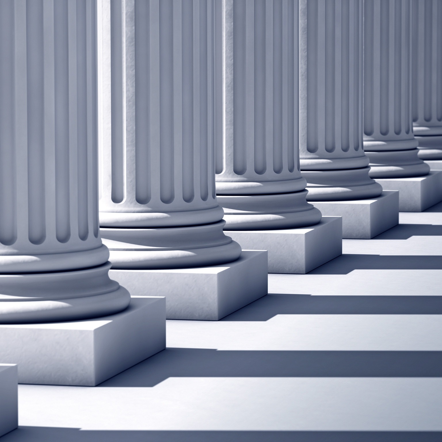 A deep row of stone columns with long linier shadows.