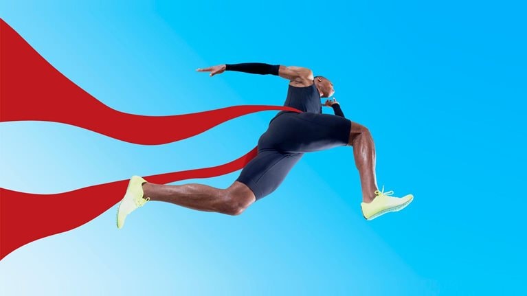 An Olympic runner crossing the finish line, the red ribbon fluttering behind him.