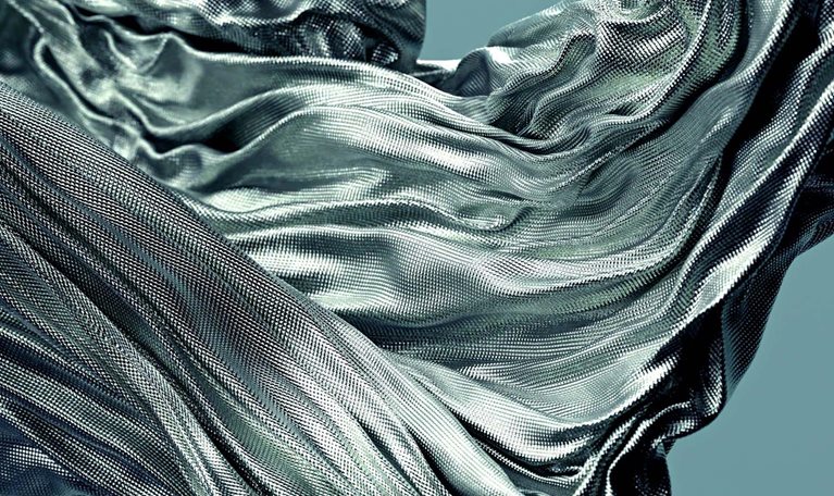 Fabric with a textured surface gracefully flowing and swirling in the air, creating dynamic folds and curves.