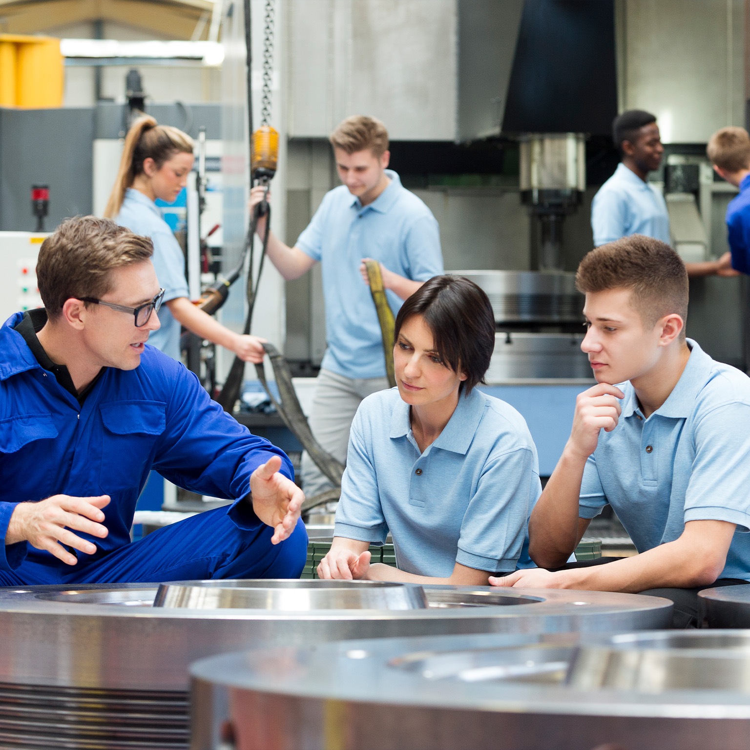 Three factory workers in workspace talking.