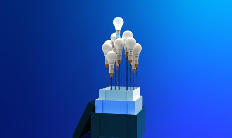 From the three stacked boxes protrudes a bouquet of about ten light bulbs, each with a base shaped like a pencil, leaving a distinct black line that resembles a flower stem. One bulb sits higher than the others, radiating a bright, glowing light.