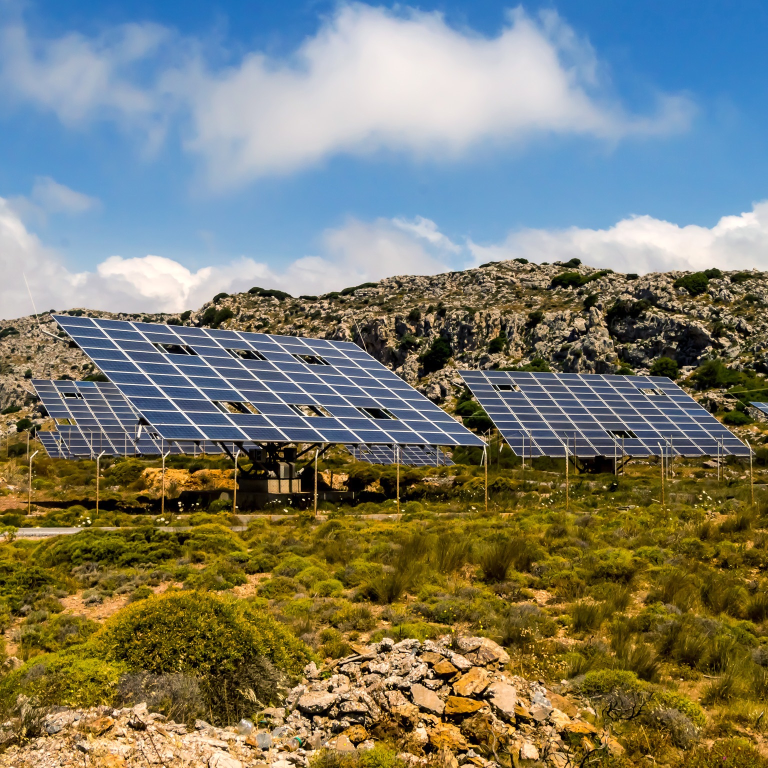 A solar farm on the foothills of a rocky terrain. 