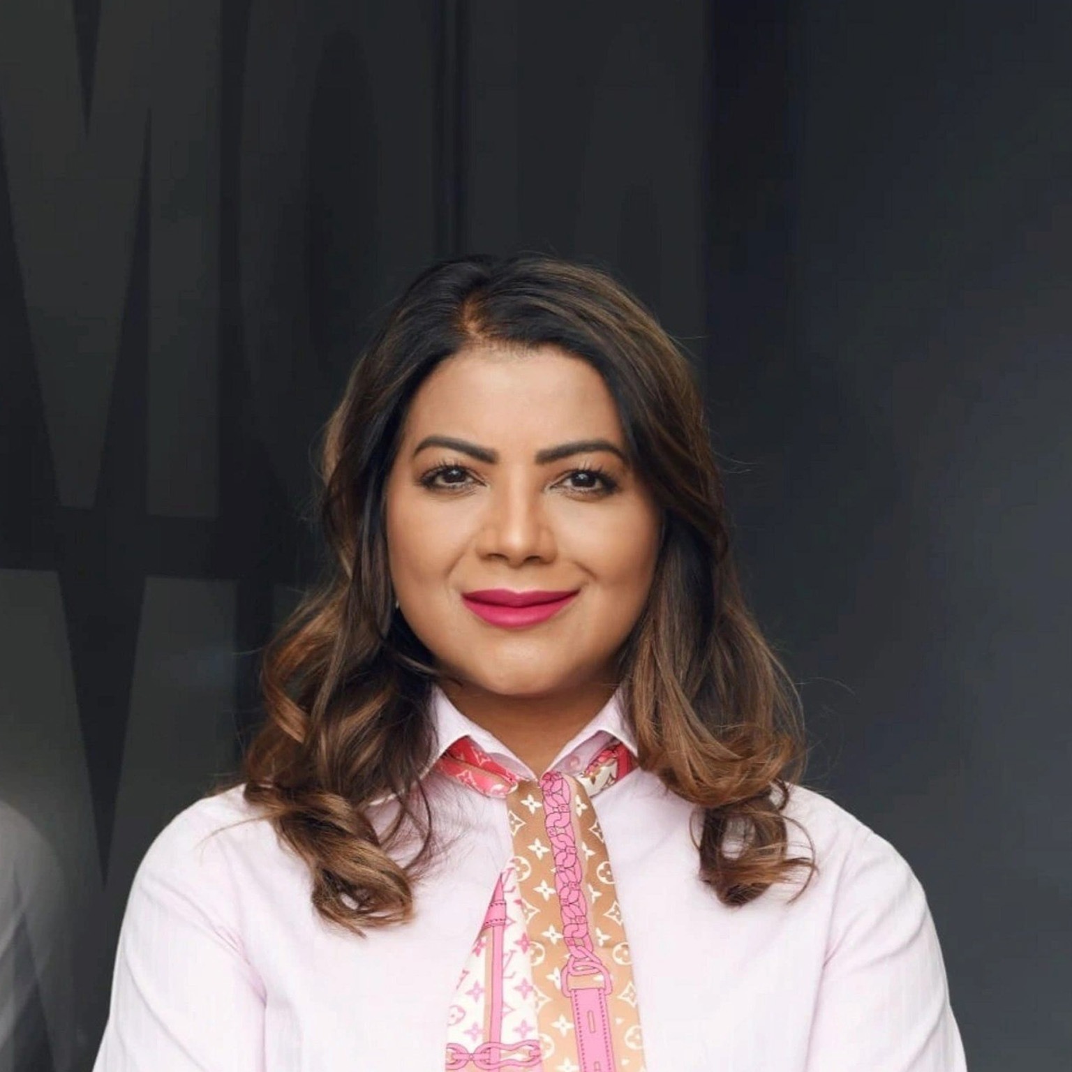 Jeniffer Ramnath with a light smile and wearing a pink top and patterned scarf. 