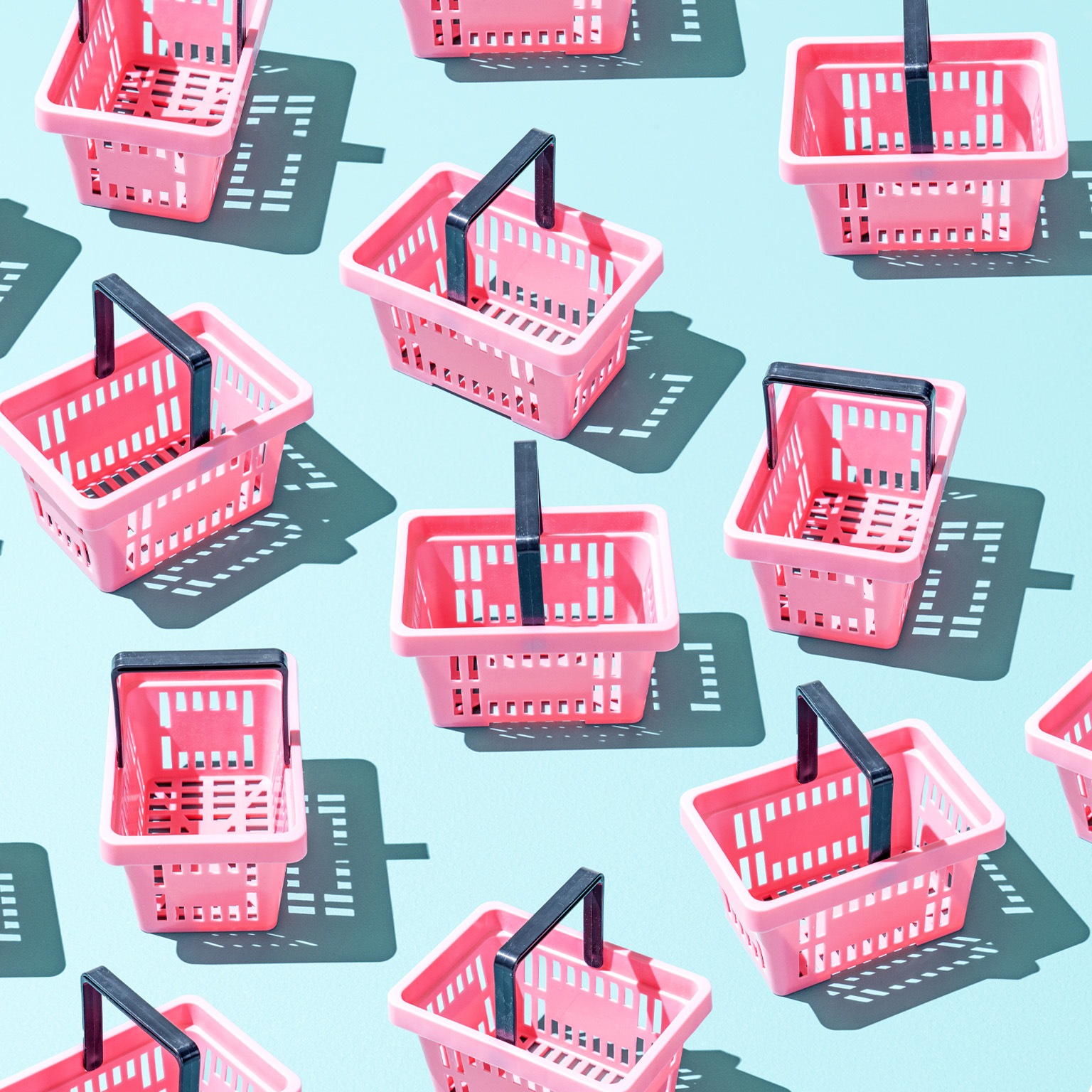 Assortment of pink plastic shopping baskets on a blue background.