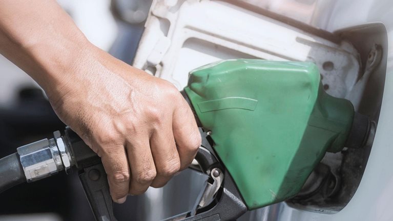 Hand holds fuel nozzle to add fuel in car