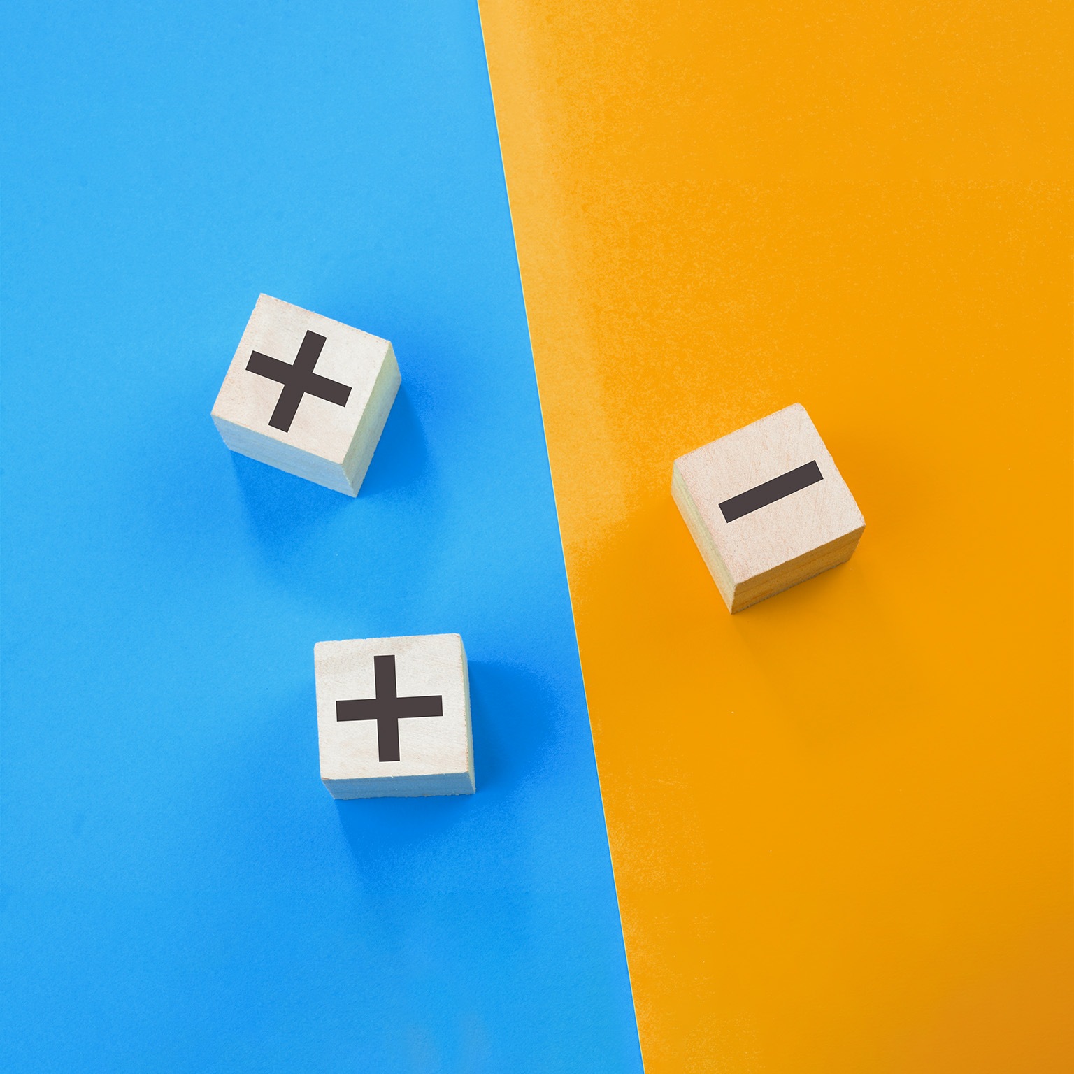 Image of 3d cubes with plus and minus signs on different sides of a colored background.
