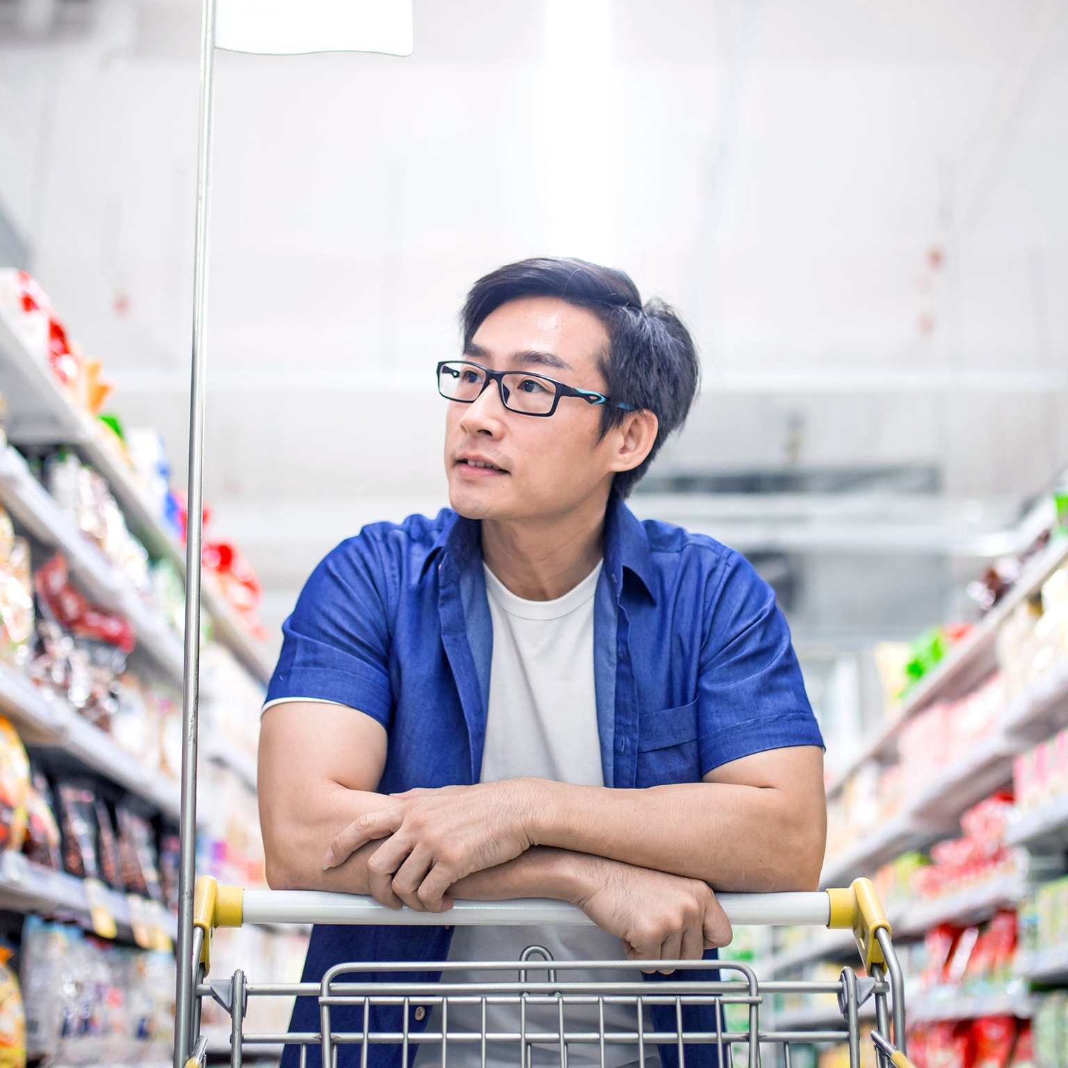 An Asia mature man pushes shopping cart and browses for products in groceries shop