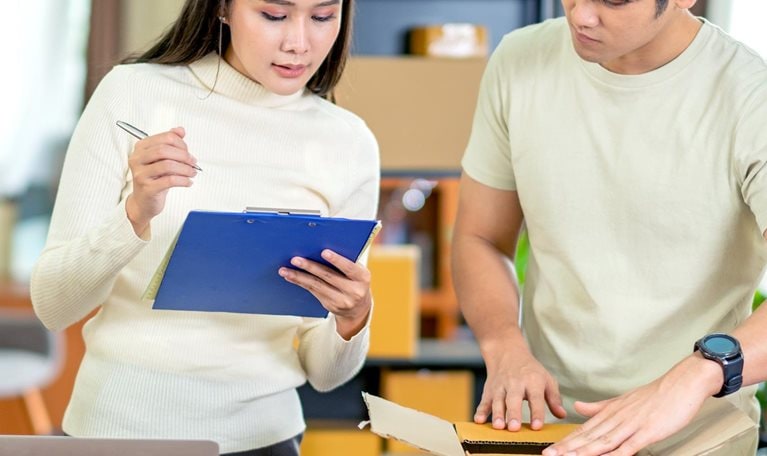 A young man and woman looking at items and checking off a list