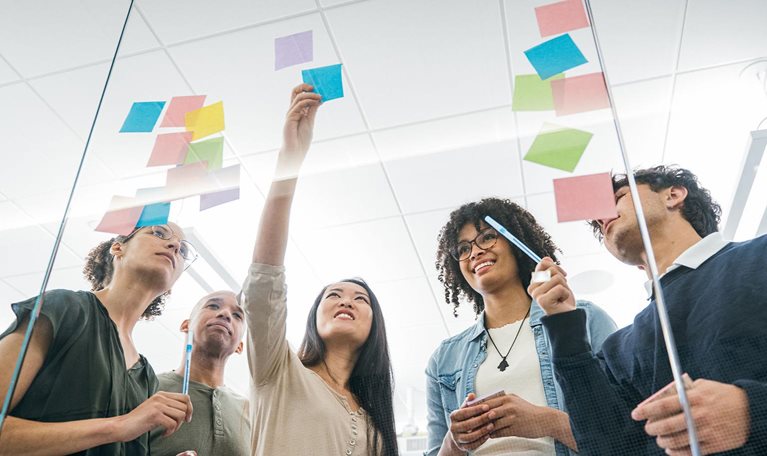 Business team brainstorming with sticky notes on glass wall