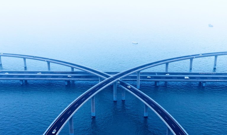 Aerial view of intersecting highway bridges over water with light traffic.