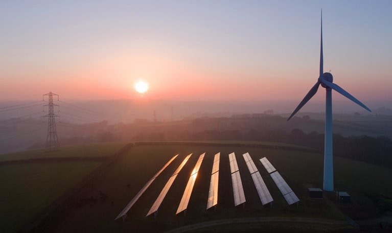 Solar panels and wind turbines in field - stock photo