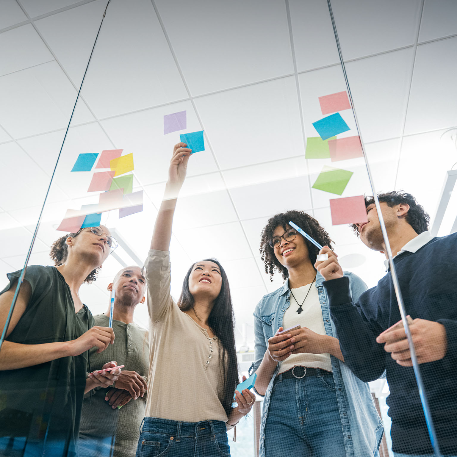 Business team brainstorming with sticky notes on glass wall