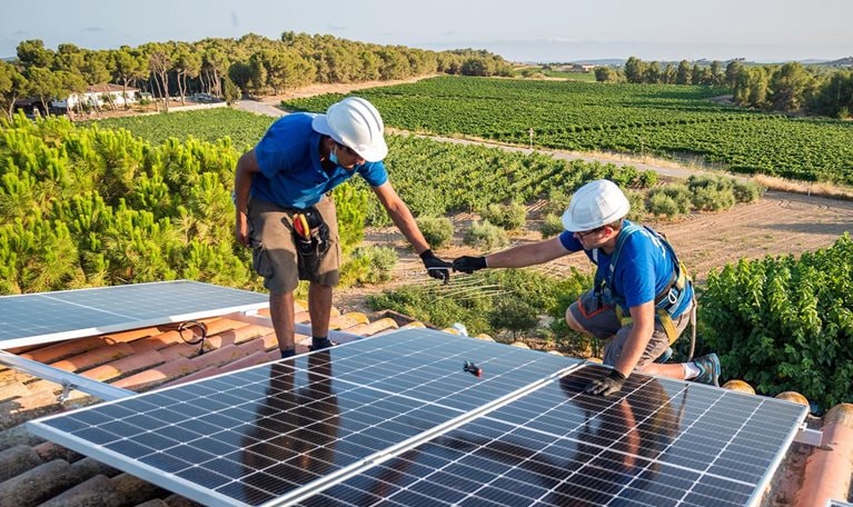 Two workers installing solar panels - stock photo