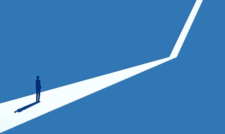 Silhouette of a person standing at the start of a branching path against a blue background.