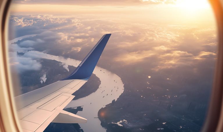 This image captures a breathtaking moment in time, showing a scenic view from an airplane window during sunset.