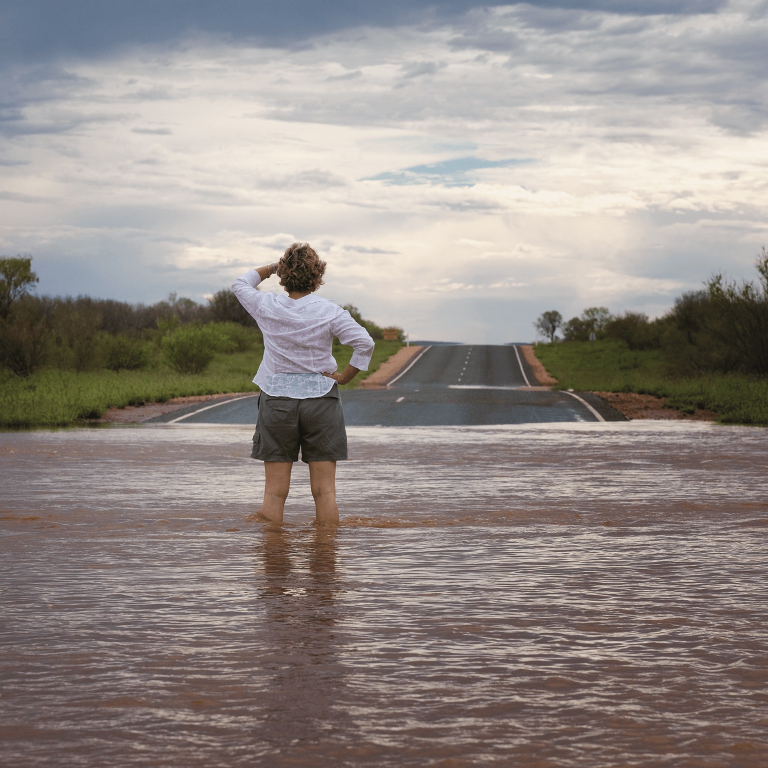 Woman stands in flooded street.