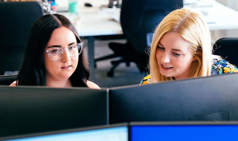 Insurance professionals collaborating at computer workstations in office setting