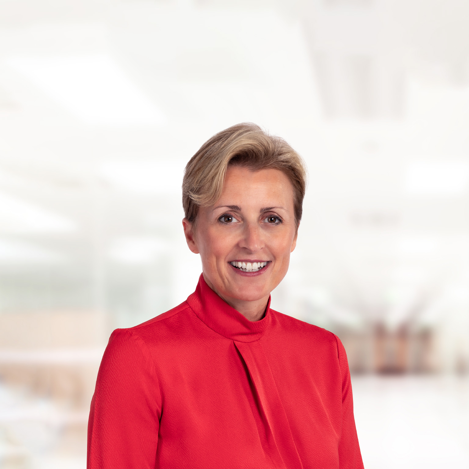  Portrait of a smiling Nikki Grady-Smith in a red high-neck blouse.