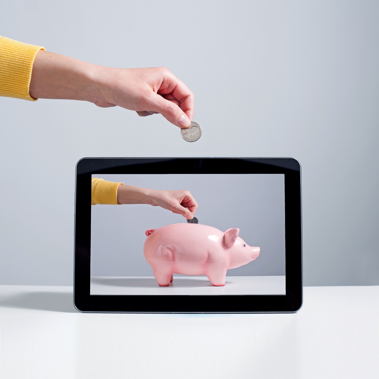 Person putting coin into digital piggy bank