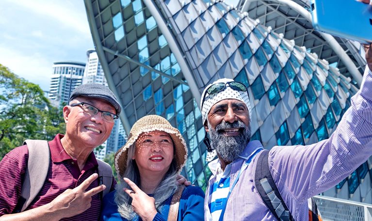 Image of two lovely senior Asian traveler having holiday photo taken by the Sikh tour guide in front of the Saloma Bridge, Kuala Lumpur.