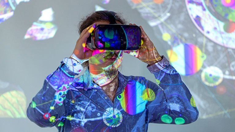 A young man wearing a VR headset with futuristic graphics projected on him.