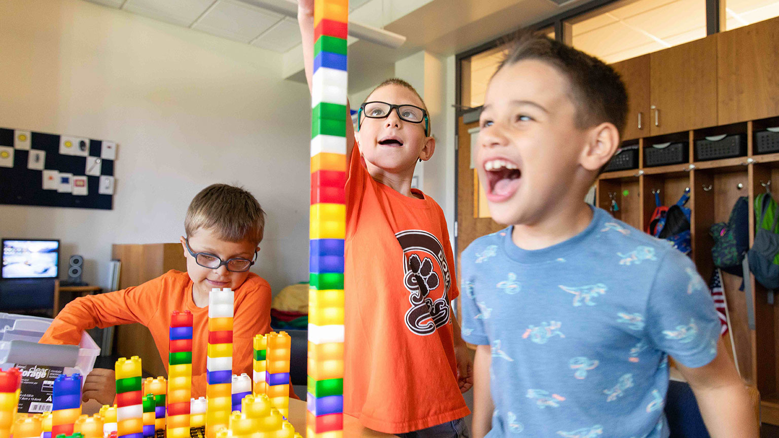Three boys joyously play with illuminated stacking blocks