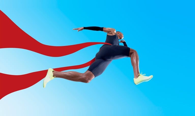 An Olympic runner crossing the finish line, the red ribbon fluttering behind him.