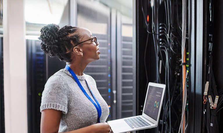 Shot of a young woman using a laptop in a server room - stock photo