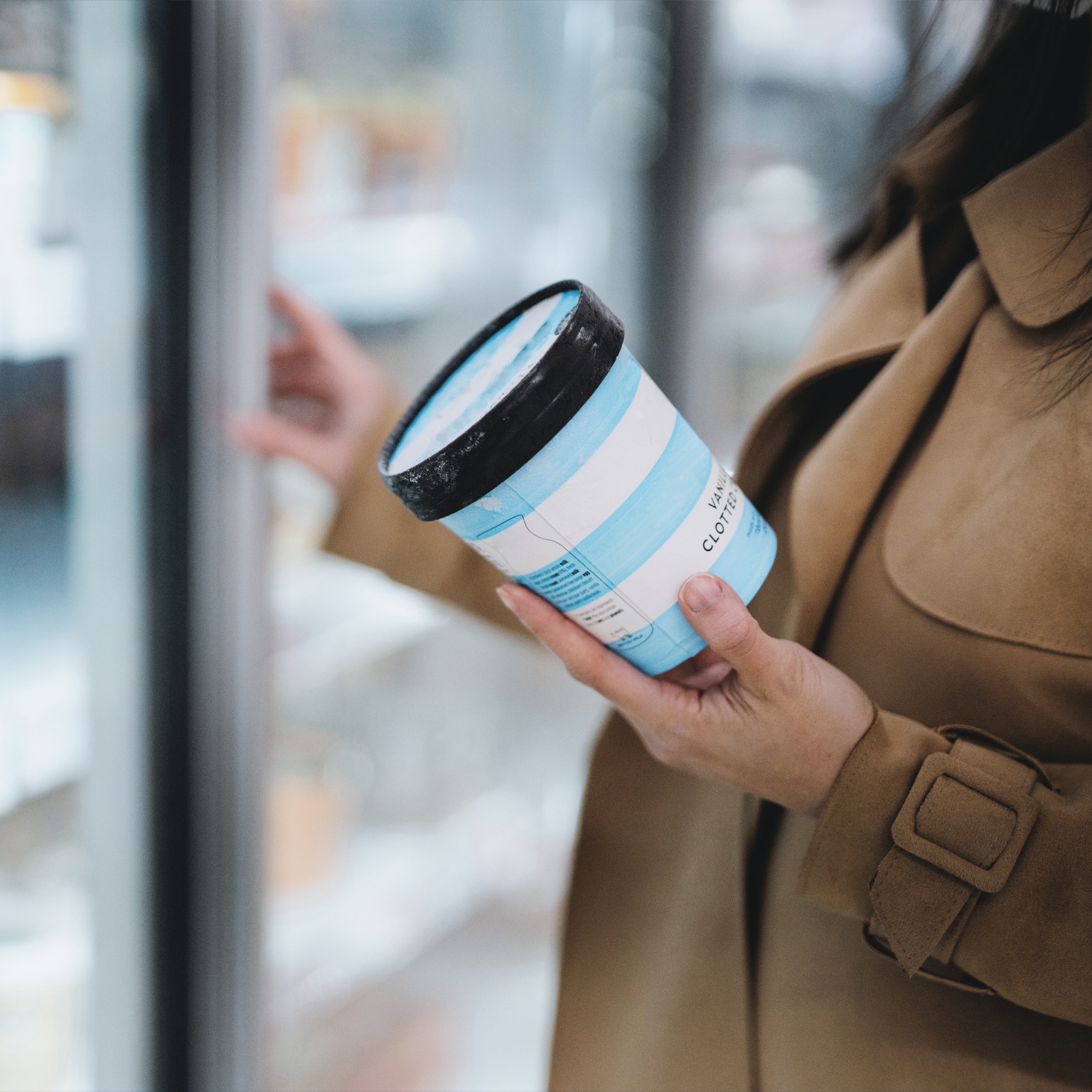 Woman holding a cup of vanilla ice cream in supermarket