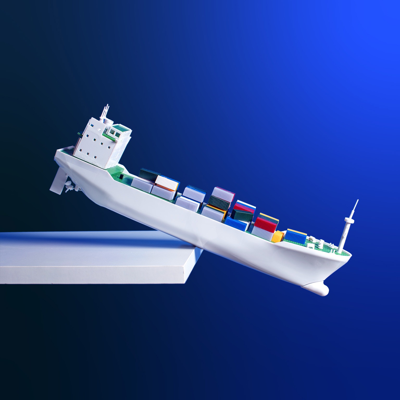 An conceptual image of a toy container ship with multi-colored containers teetering on the edge of a shelf.