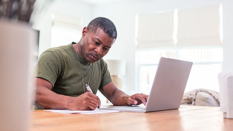 Serious mature adult soldier takes continuing education courses online using his laptop.