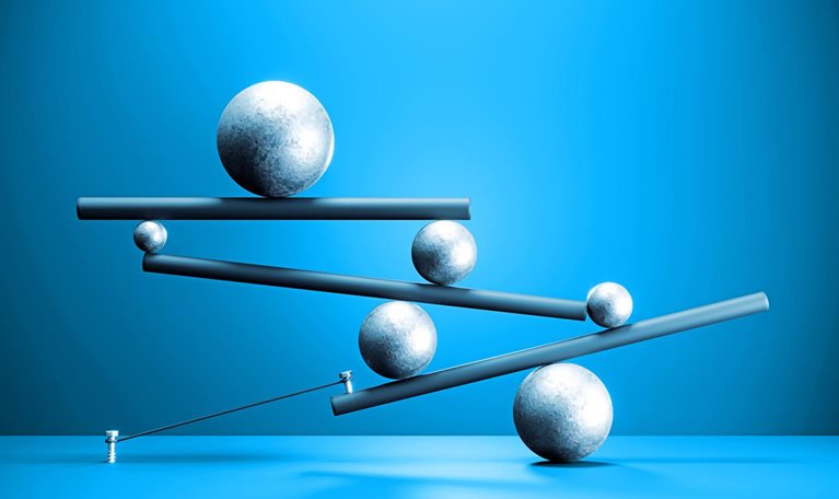 Several spheres of different sizes are balanced across tilted beams, forming a delicate, interconnected structure. The composition against a blue background suggests tension and the careful balancing of forces.