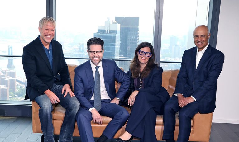 Photograph of Carolyn Dewar, Kurt Strovink, Scott Keller, and Vik Malhotra sitting together in a modern office.