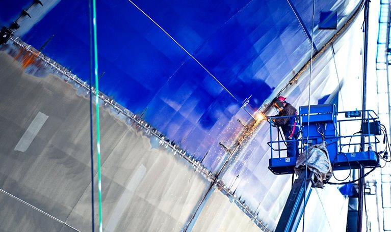 Low angle view of worker welding ship at industry