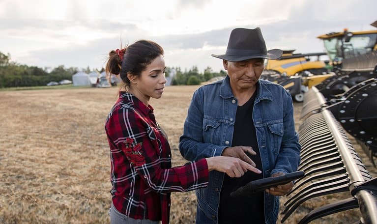 Farmer couple with digital tablet at combine harvester on farm - stock photo