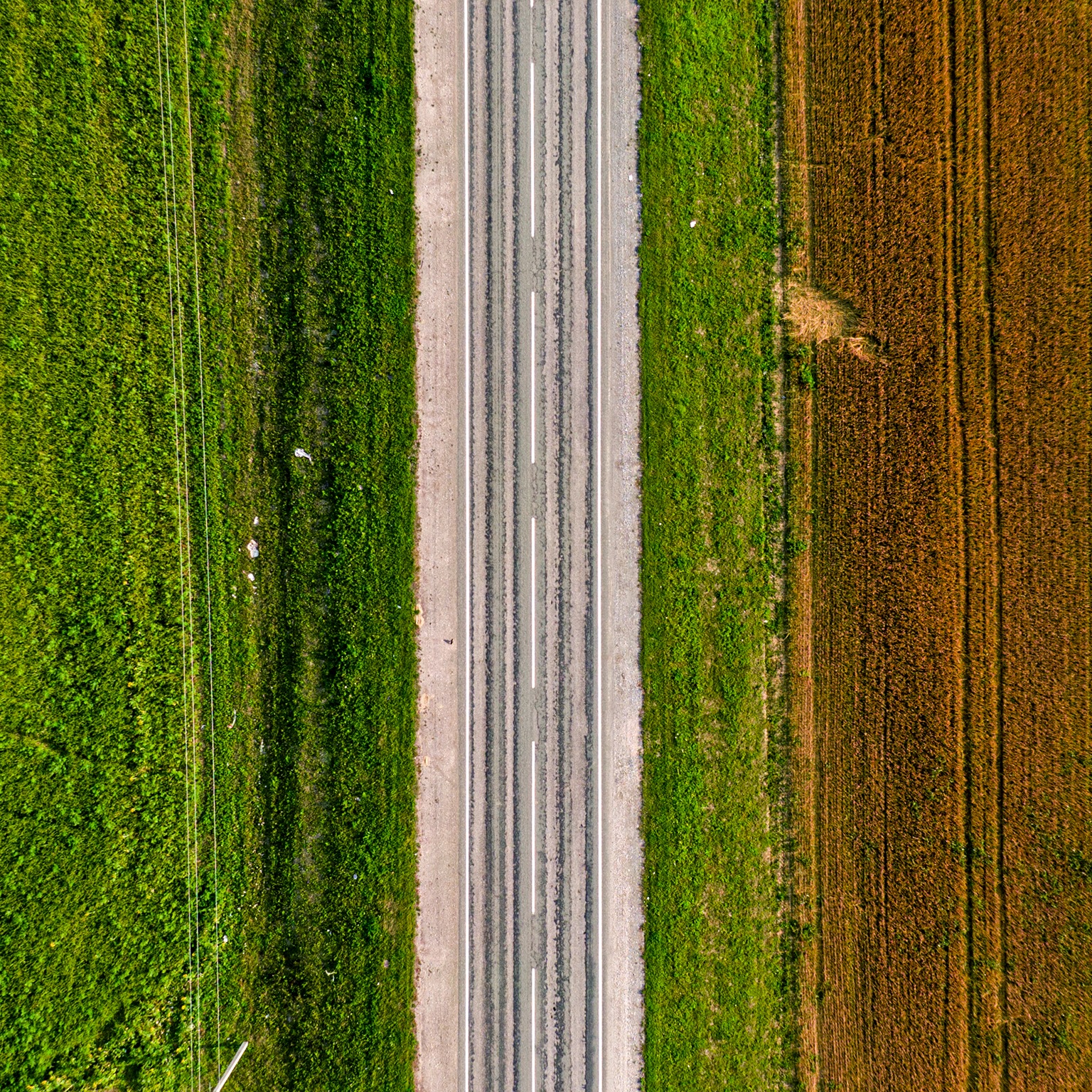 Aerial shot of an empty highway on a green and brownfield