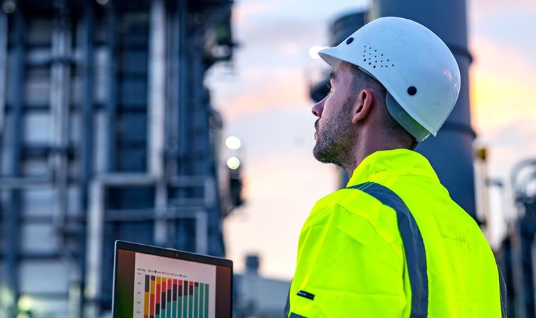 An industrial engineer using a laptop to monitor operational data at a facility.