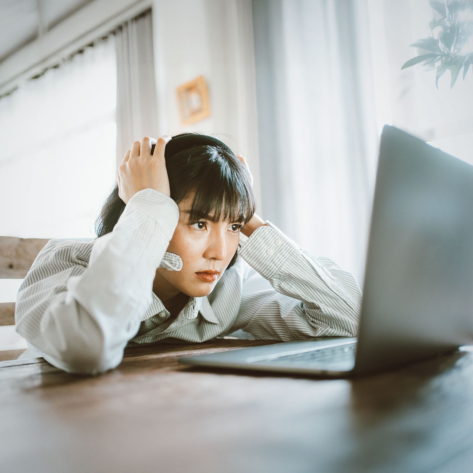 This image shows a person appearing stressed or frustrated while working on a laptop computer, representing professional challenges.