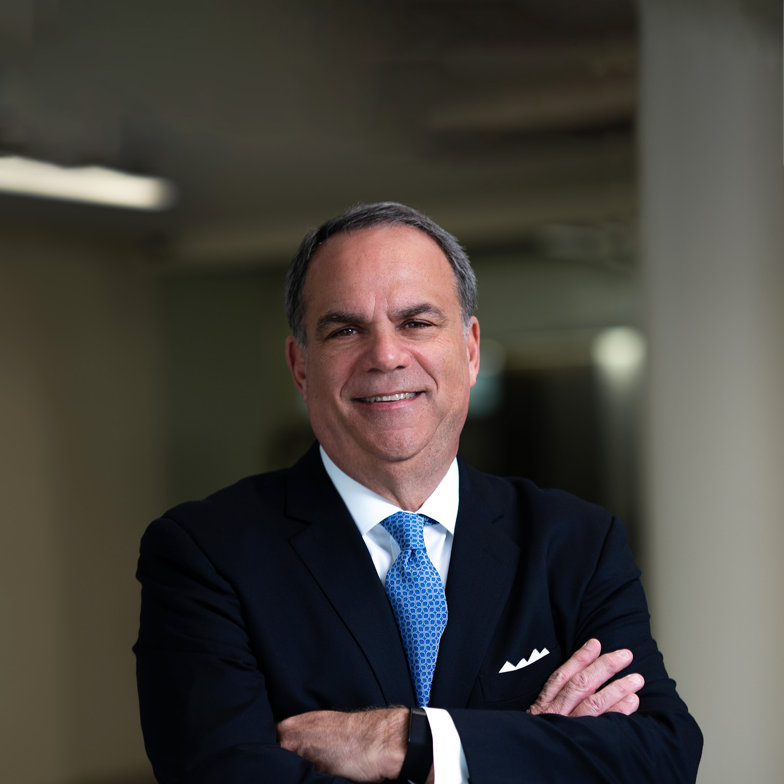 Portrait of smiling Bob Trunzo with his arms crossed and a dark business suit.