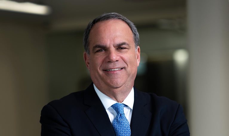 Portrait of smiling Bob Trunzo with his arms crossed and a dark business suit.