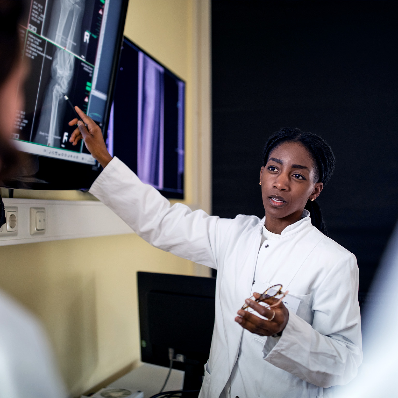 Female surgeon discussing patient's scan and diagnosis with colleagues