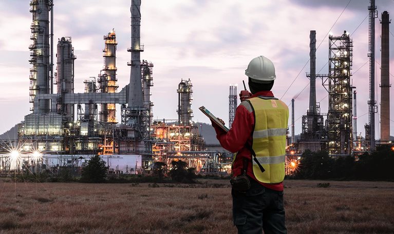The image shows an engineer or safety professional at a petrochemical or industrial plant.