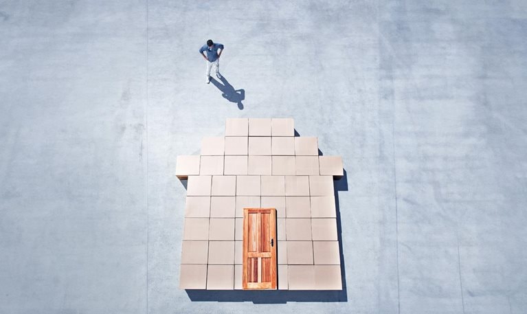 Man standing next to house outline on sidewalk - stock photo