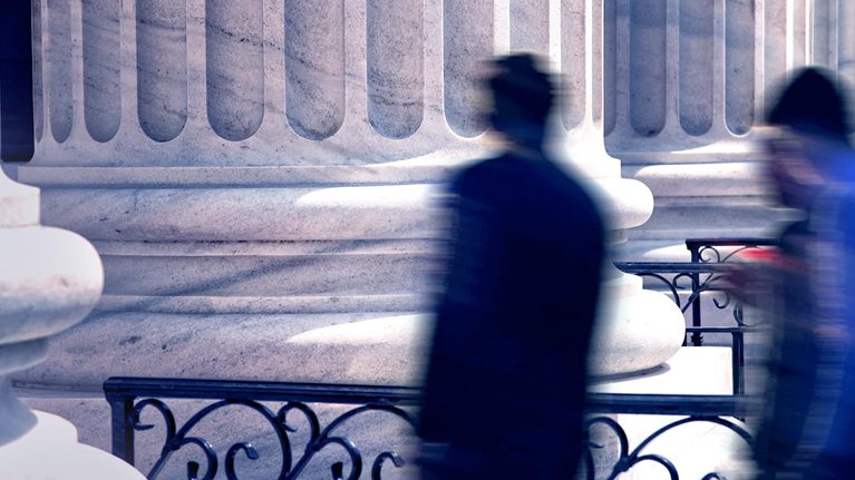 Blurred motion busy people and office building exterior - stock photo