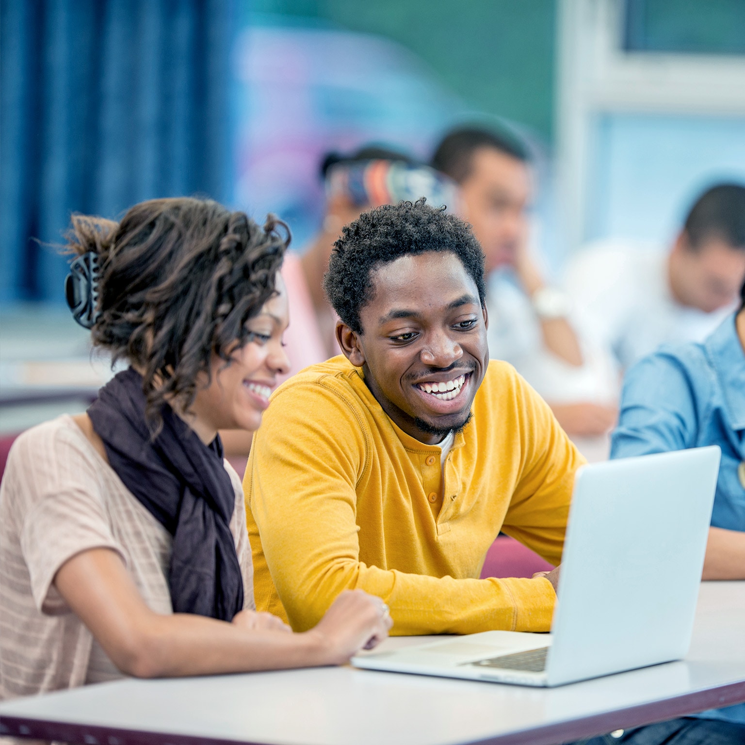 A multi-ethnic group of college age students surfing the web and researching a paper together. - stock photo