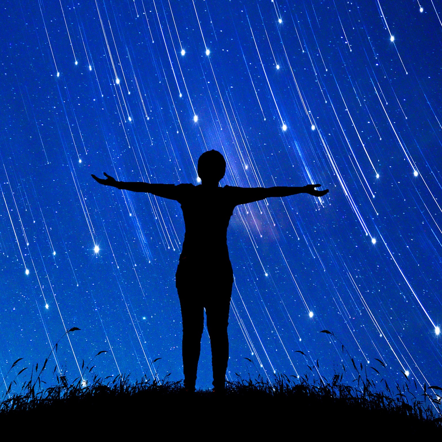  A girl standing with her arms open to a sky full of shooting stars